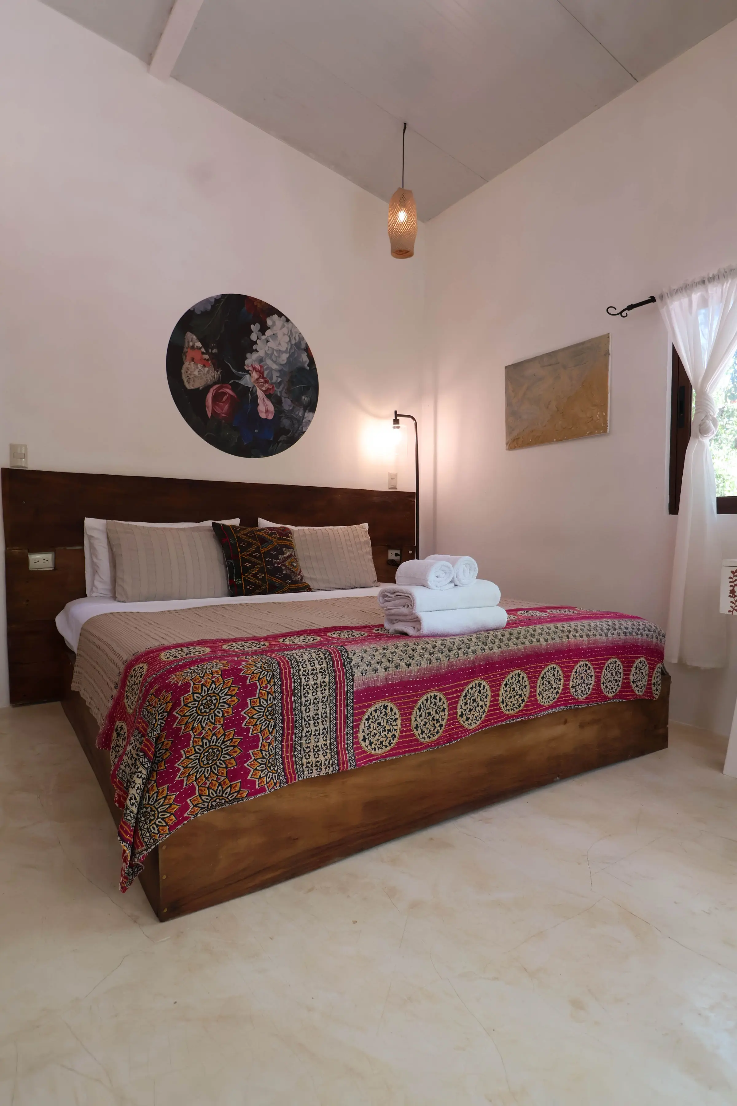 The bed in a King Room at Naya Nosara, with a round painting above the wooden headboard